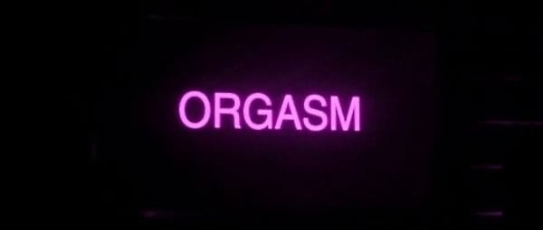 Pink neon sign displaying the word 'ORGASM' against a dark background.