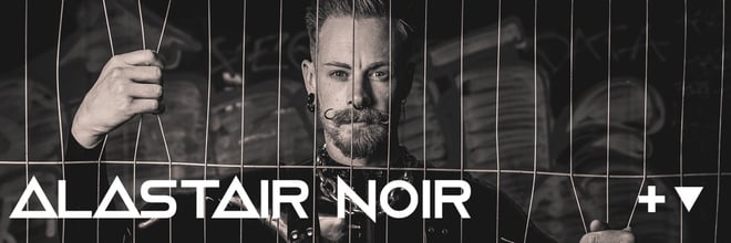 Black and white portrait of a man with a beard gripping metal bars, with his name overlaid in bold text against a dark background.