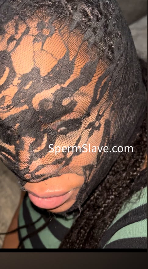 Close-up portrait of a woman wearing a patterned lace face mask and green top against a dark background.