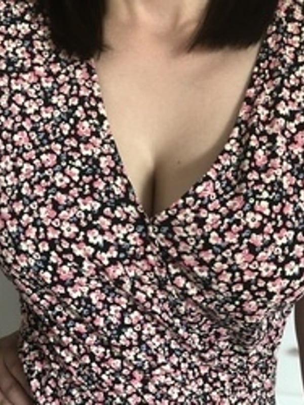 A woman in a floral print top posing indoors with hands on hips.