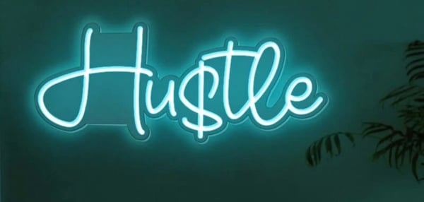 Neon sign displaying the word 'HUSTLE' in glowing cyan letters against a dark green background with a plant nearby.