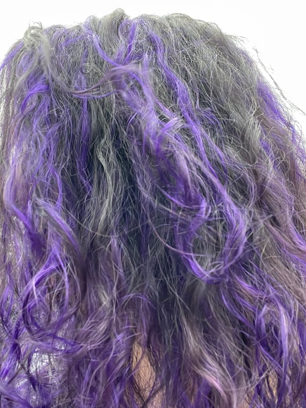 Close-up of a woman with long wavy purple-dyed hair.