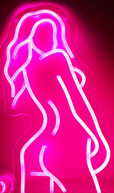 Neon pink silhouette of a woman with long wavy hair posing with curves accentuated against a dark background.