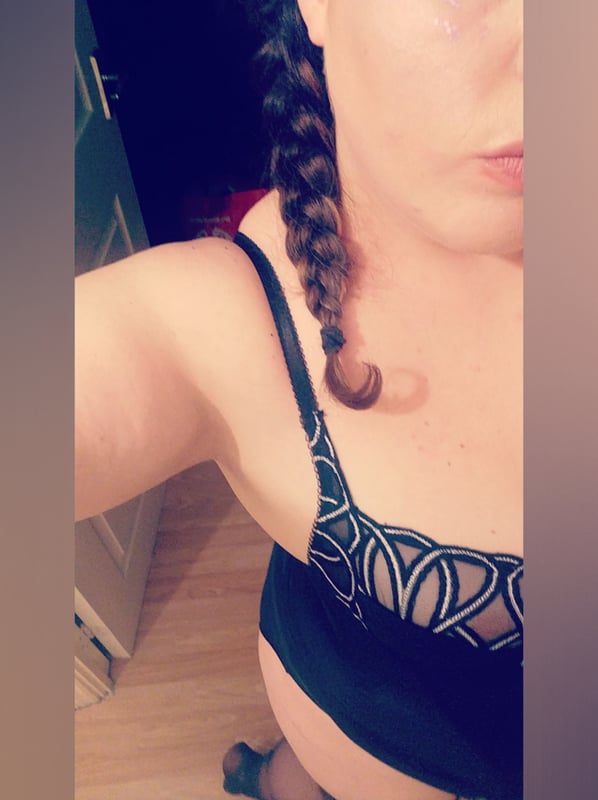 Woman with braided hair posing indoors in a lace top and stockings near a door.