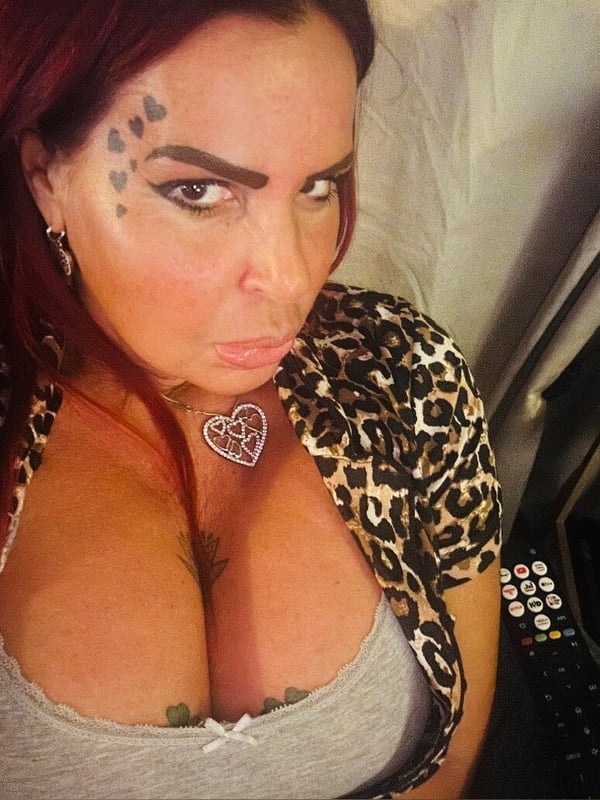 Close-up portrait of a woman with red hair and bold makeup wearing a leopard print top.