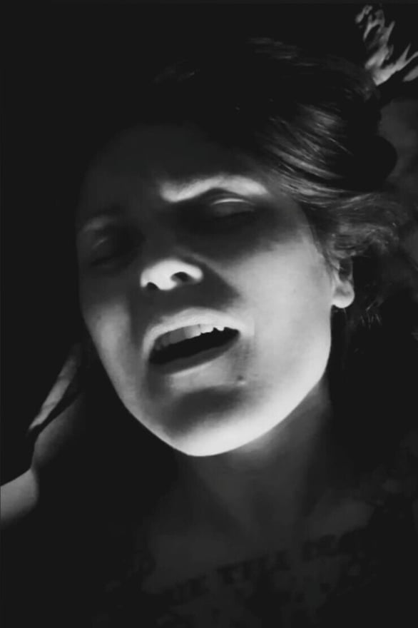 Black and white close-up portrait of a woman with long hair, eyes closed, and mouth open in an expressive pose under dramatic lighting.