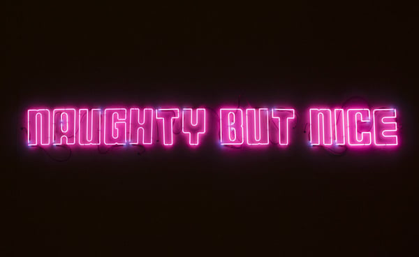 Pink neon sign displaying the text 'Naughty but nice' on a black background.
