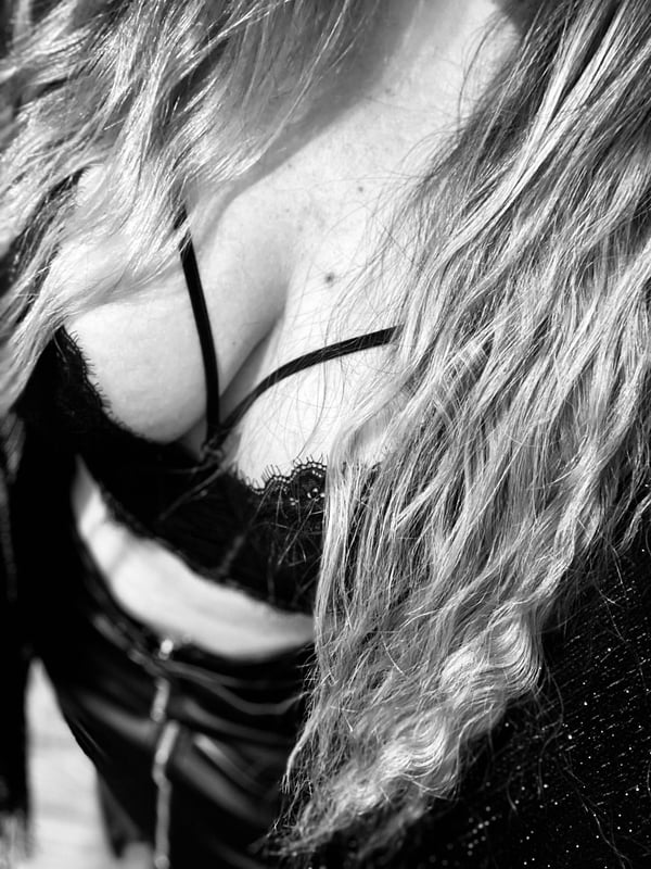 Close-up black and white portrait of a young woman with long blonde hair wearing black lace lingerie.