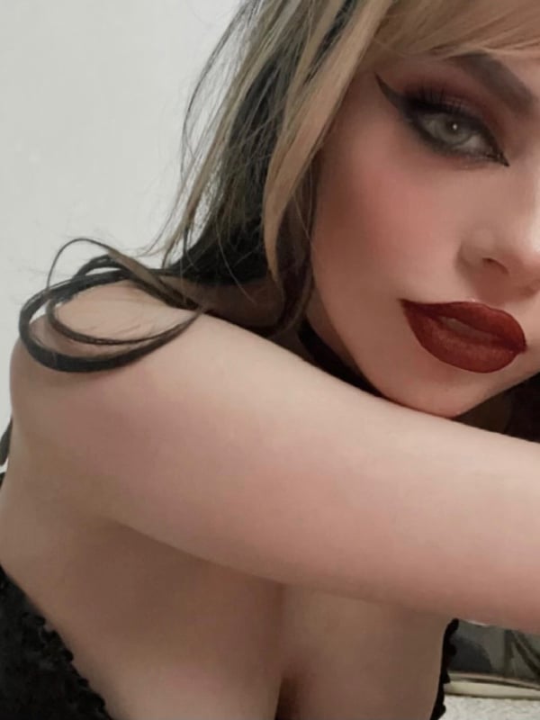 Close-up portrait of a woman with dramatic makeup and dyed hair.