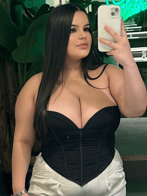 A close-up selfie of a woman with long dark hair wearing a black top.
