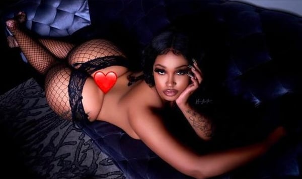 A woman posing on the floor in a blue bikini and high heels against a dark background.