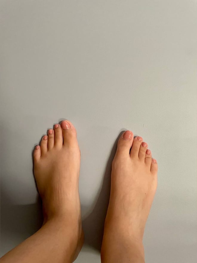 Close-up view of a person's bare feet positioned on a plain light gray background.