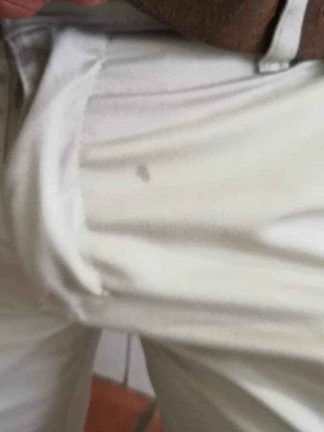 Close-up of a person in white pants with a brown belt, focusing on the lower body.