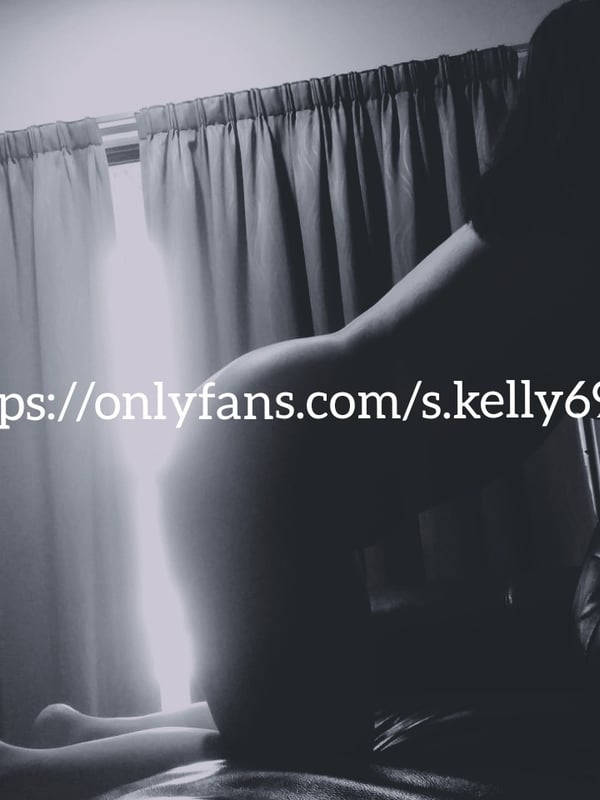 Silhouette of a woman posing on the floor in a dimly lit room with curtains and soft backlighting.