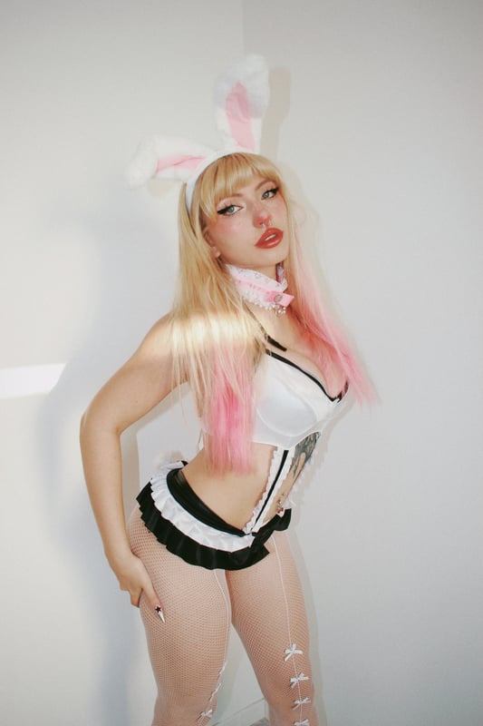 Close-up of a person in shiny black latex clothing with dramatic pink lighting.