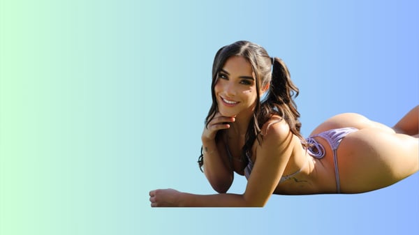 A woman with long dark hair in pigtails poses smiling on the floor in a colorful bikini against a blue gradient background.