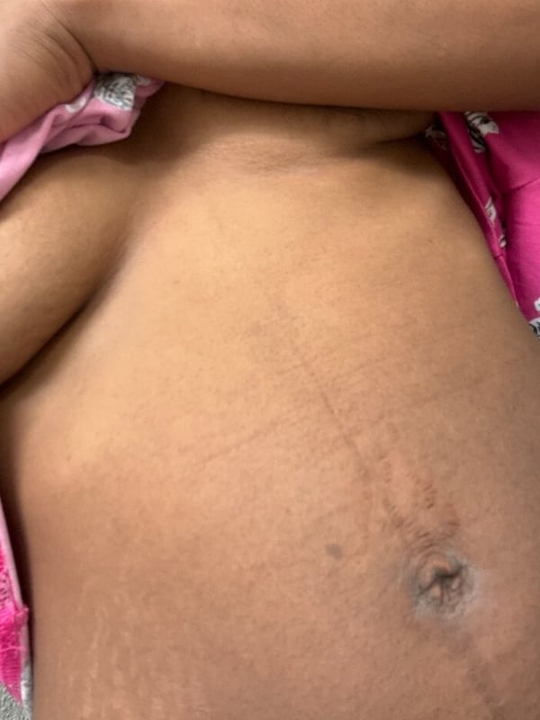 Close-up of a woman's upper body wearing a pink top, highlighting her midsection.