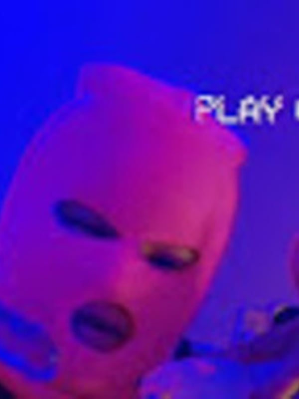 Close-up of a person wearing a pink balaclava mask with neon 'PLAY' text overlay on a vibrant blue background.