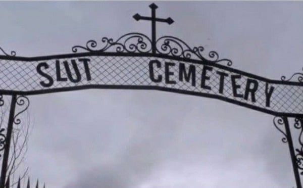 Ornate wrought iron gate with 'Slut Cemetery' inscription and cross detail against a cloudy sky.