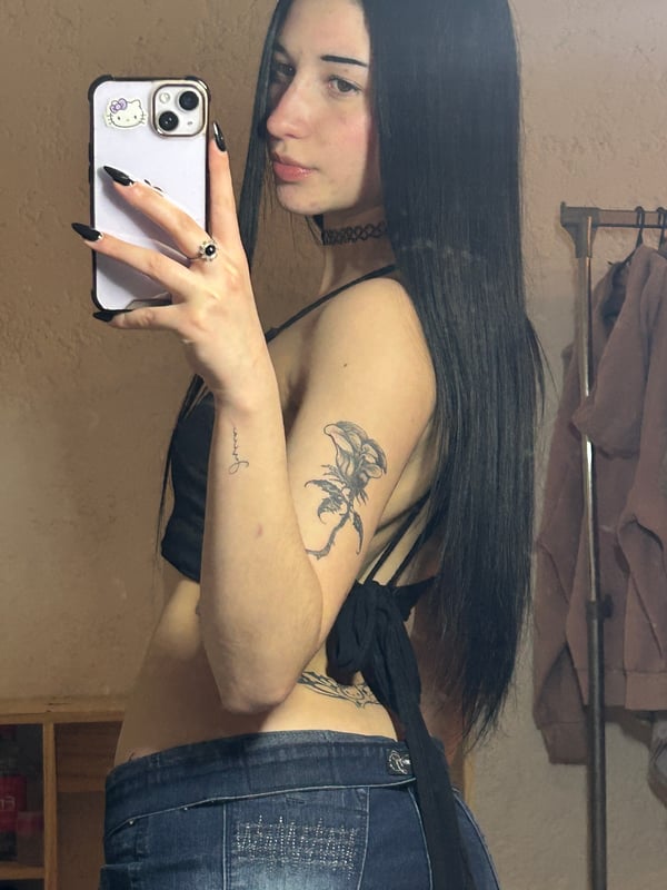 A person with dark hair taking a selfie in a bedroom setting.