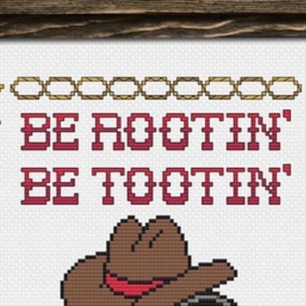 A cross-stitched sign with cowboy ropes and text reading 'Be Rootin' Be Tootin', featuring a cartoon cowboy hat.
