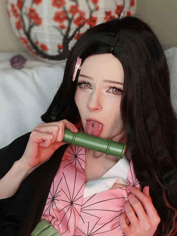 Close-up of a person in detailed cosplay attire featuring a bamboo prop, set against a room with traditional lanterns and soft lighting.