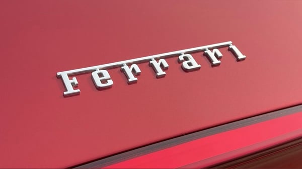 Close-up view of a red Ferrari logo on the hood of a luxury sports car.