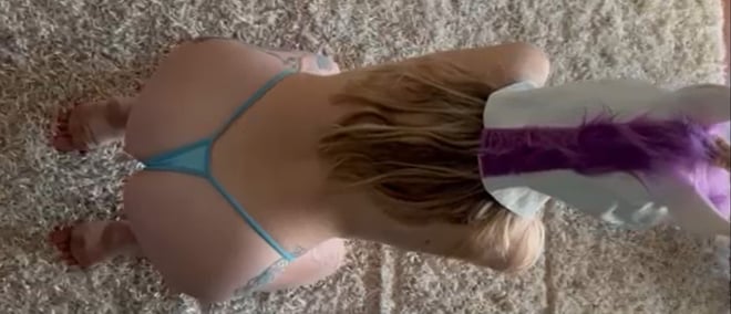 A person kneeling on a carpeted floor in a swimsuit, viewed from behind with hands and feet visible.