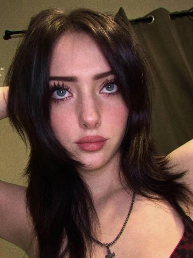 A brunette woman posing for a close-up portrait indoors.