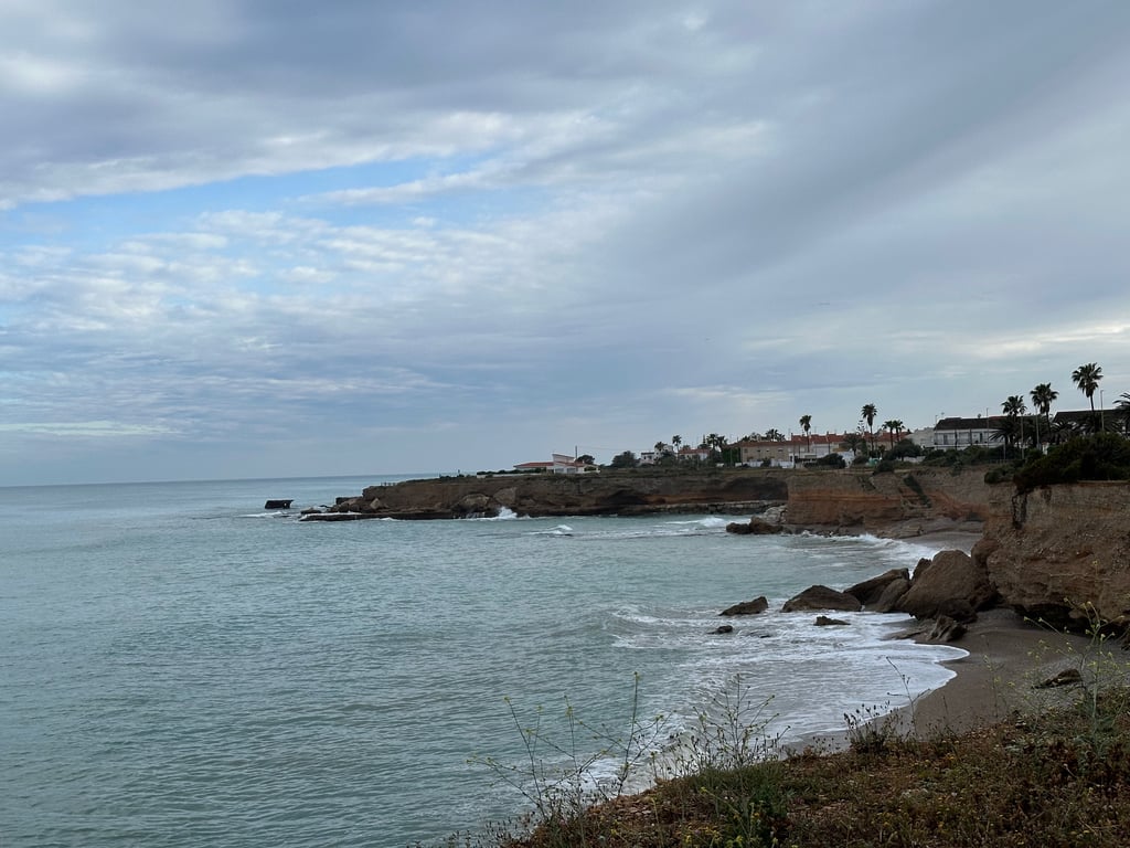 Dramatic Cliffs and Calm Sea Under Cloudy Skies