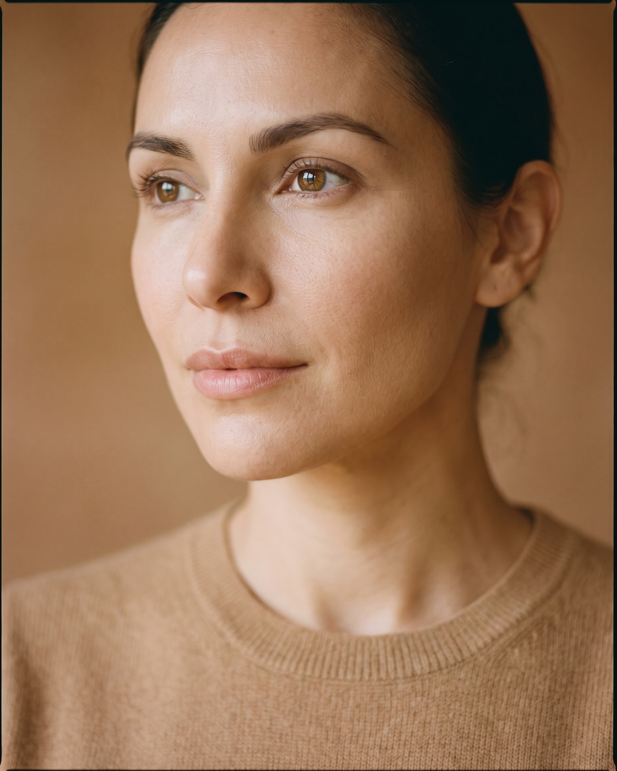 Close crop of a cheekbone, temple and open eye in broad soft light, the upper cheek reading full and evenly modelled.