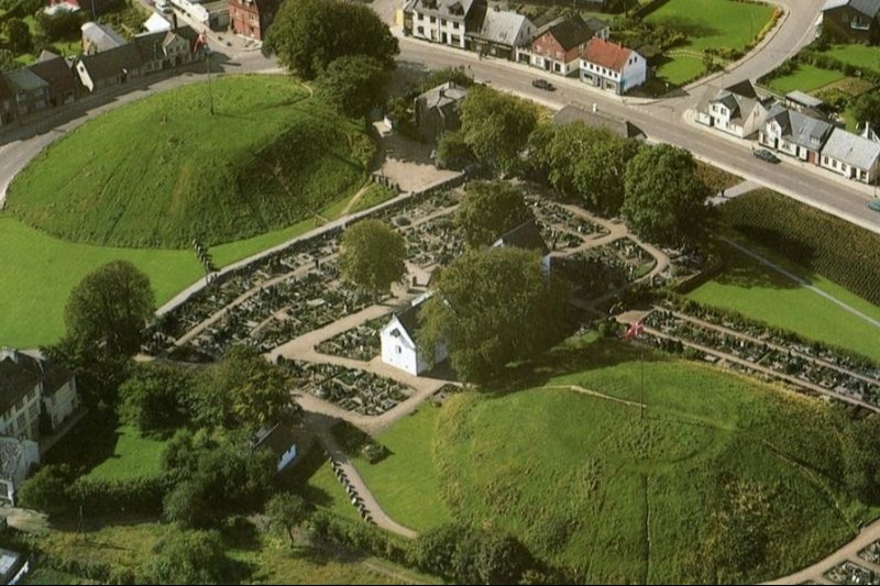 Jelling, Harald Bluetooth’un Danimarka’daki ilk saltanatının odak noktasıydı. Alana iki büyük tepe hakim.&nbsp; Aralarında yer alan ve MS 1100 civarında inşa edilen kilise, daha önce inşa edilmiş üç kilise yapısının üzerine inşa edilmiş. Kuzey tümülüsün altında 958 yılına tarihlenen etkileyici bir mezar odası bulunuyor. Artık boş olan bu odada, muhtemelen bir zamanlar Bluetooth’un babası Gorm’un cesedi bulunuyordu.