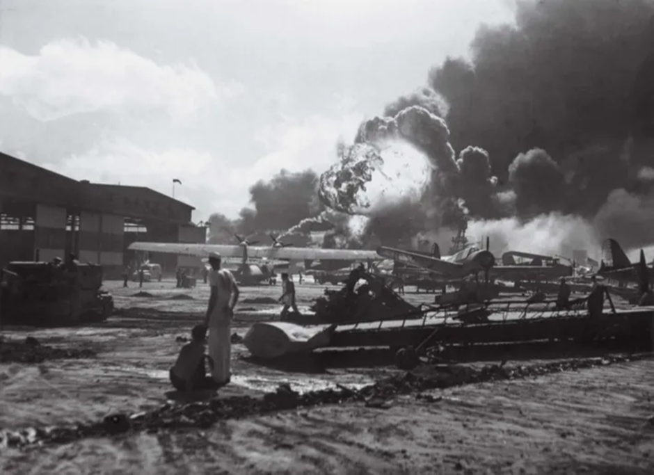 Bir denizci, Pearl Harbour'a yapılan Japon saldırısı sırasında Ford Adası Deniz Hava Üssü'ndeki patlamaları gözlemliyor ve enkazın ortasında duruyor.