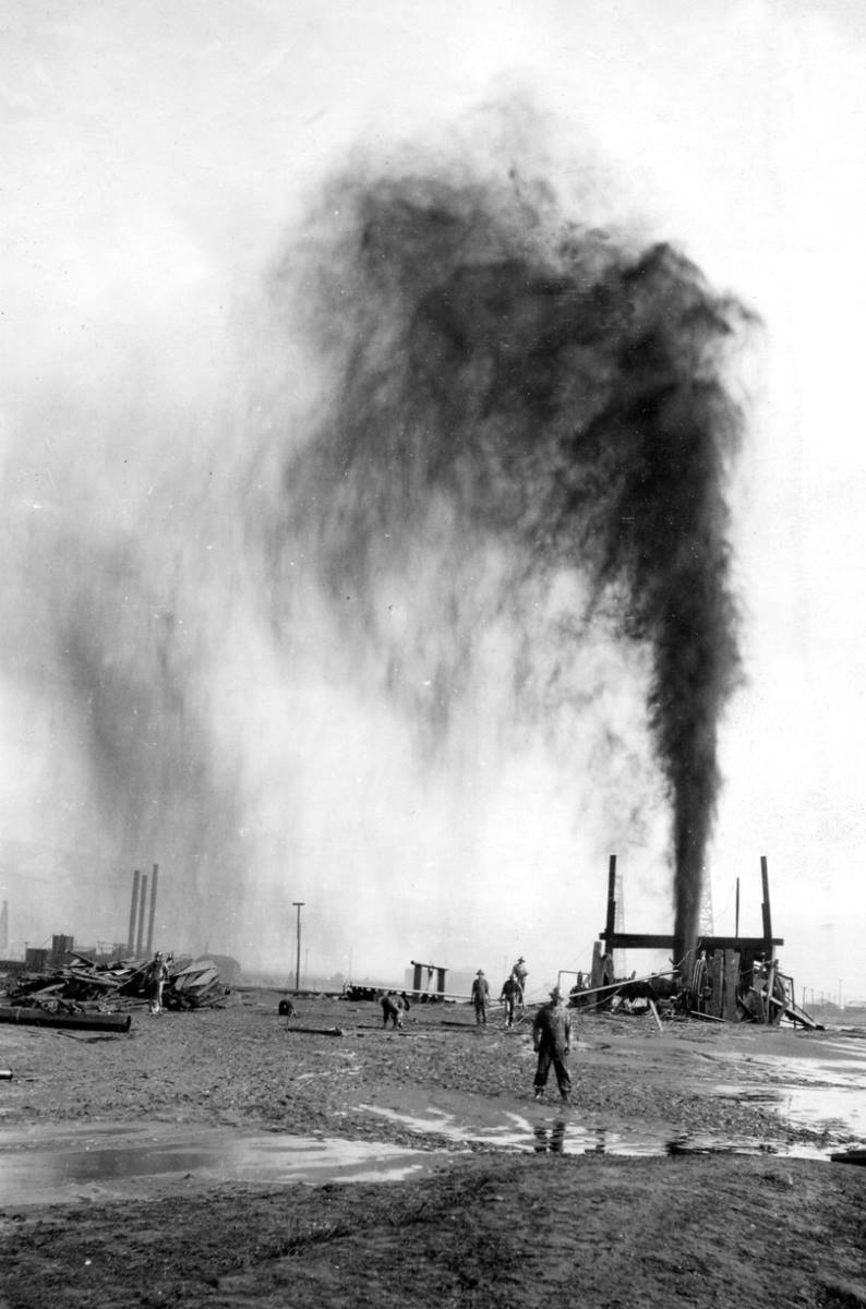 Bir işçi kaçak petrol kuyusunun önünde poz veriyor.