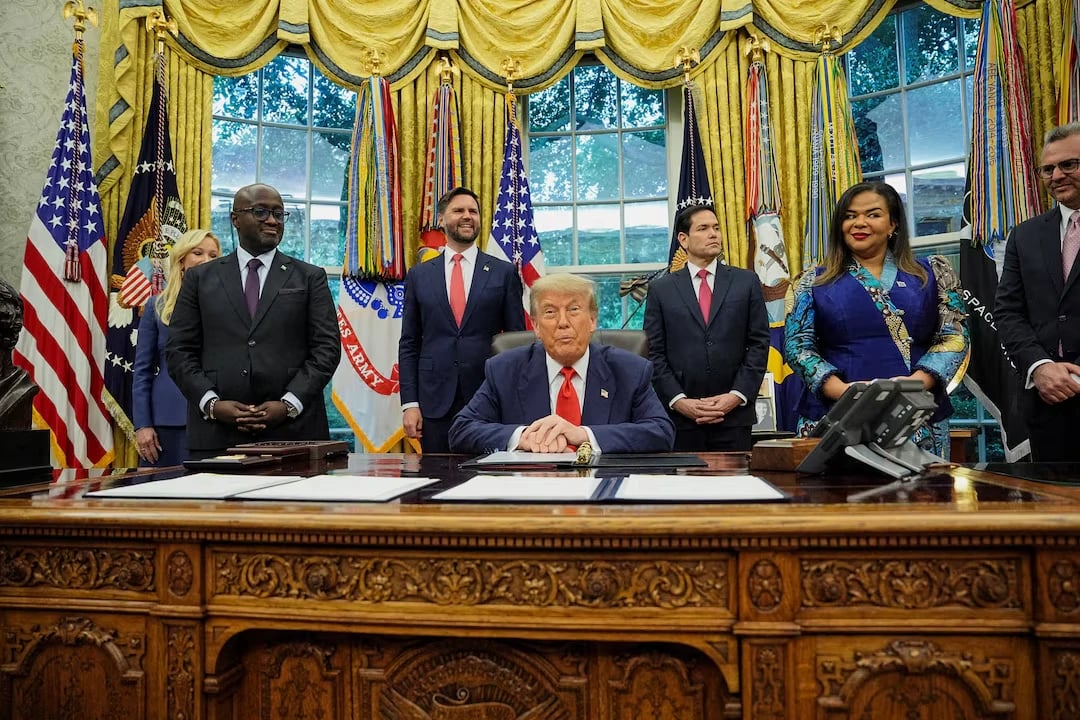 U.S. President Donald Trump is flanked by Rwandan Foreign Minister Olivier Nduhungirehe (left foreground) and Congolese Foreign Minister Therese Kayikwamba Wagner (right foreground) in the Oval Office on June 27, 2025.