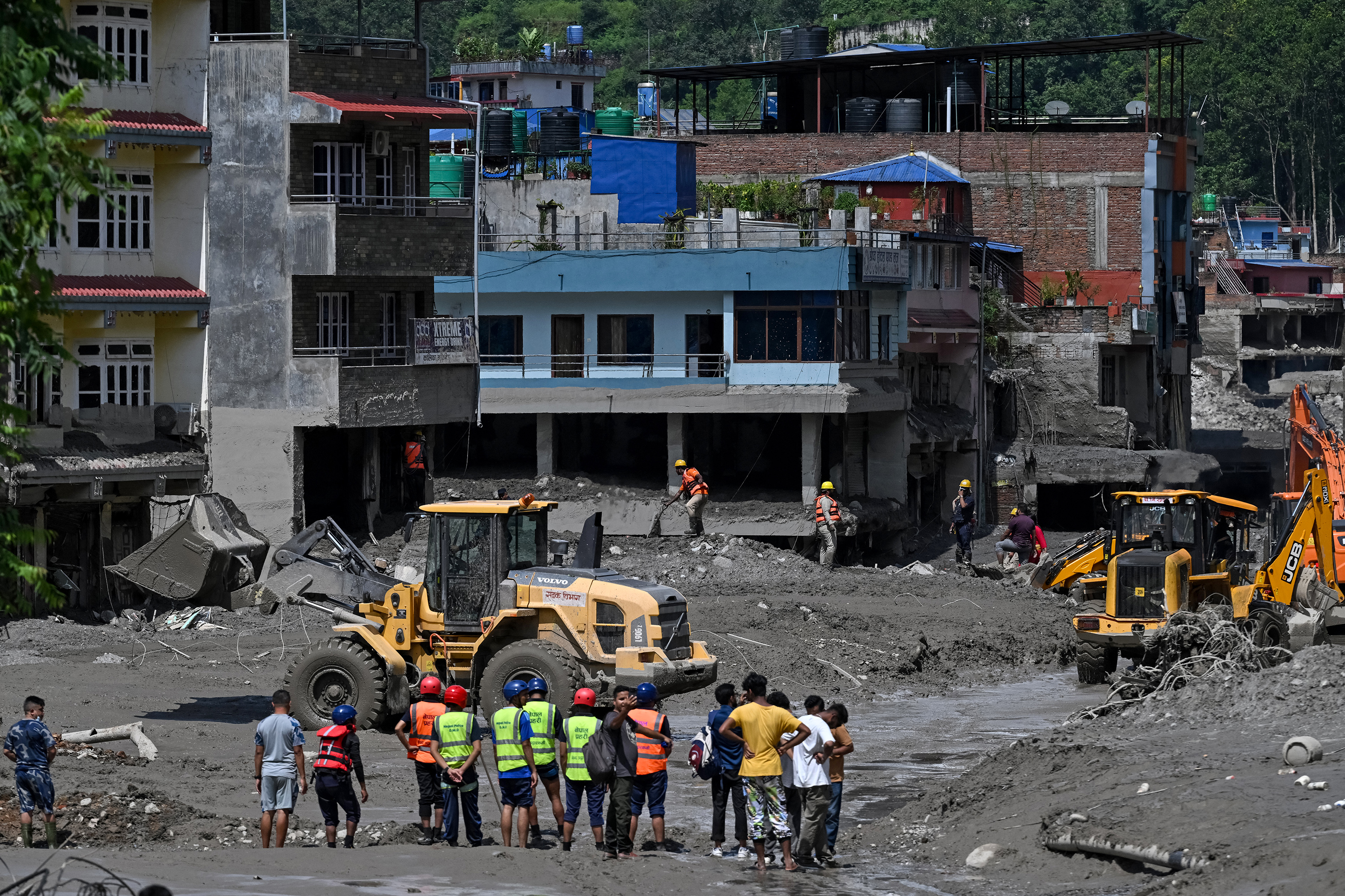 Volunteers using bulldozers to clear mud and debris along a road after flash floods at Trishuli in Nepal, Aug. 27, 2026 - AFP