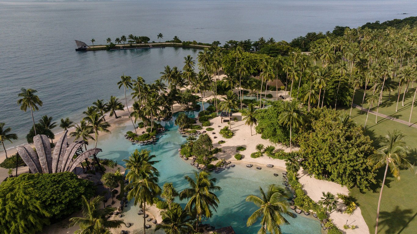 Overwater bungalows with thatched roofs extending into the clear blue ocean