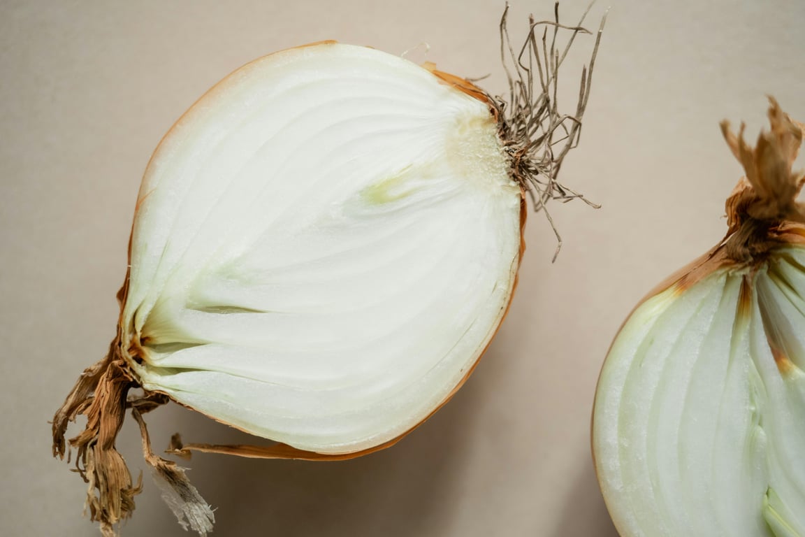 High-resolution close-up of a halved white onion on a neutral background, showcasing texture and detail.