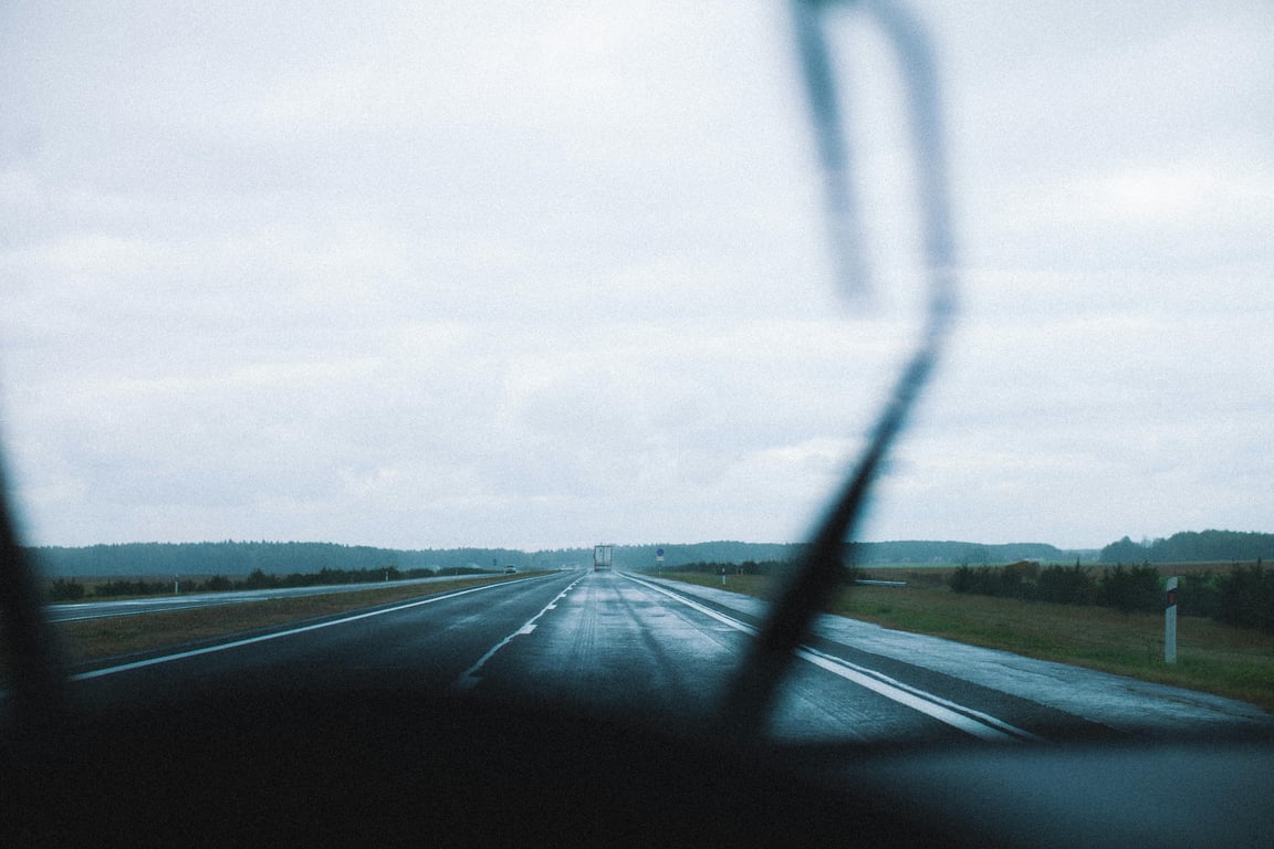 View of a long highway through a rainy windshield, capturing the essence of travel.