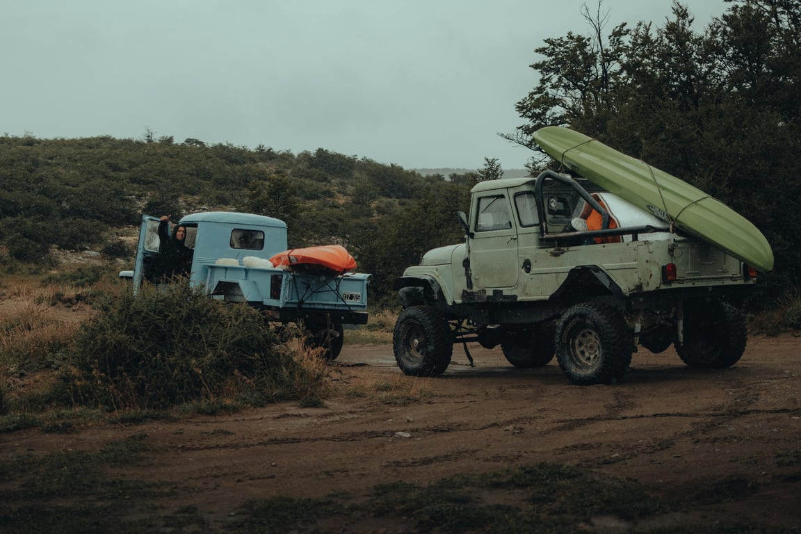 Two 4x4 trucks with kayaks secured, set for a rugged off-road journey.