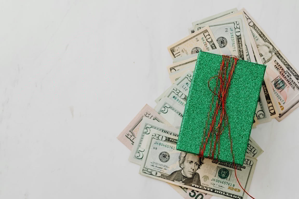 Green gift box on a pile of dollar banknotes showcasing a concept of monetary value and gift-giving.