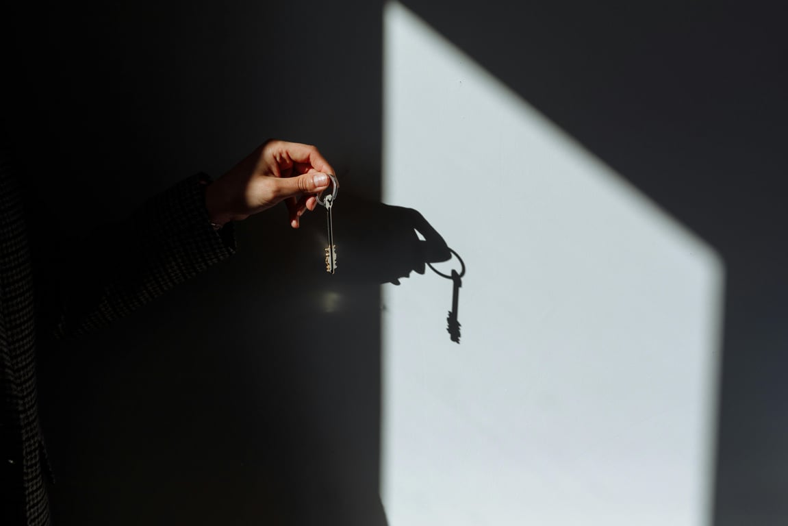 Minimalist photo of a hand holding a key casting a shadow, signifying property ownership