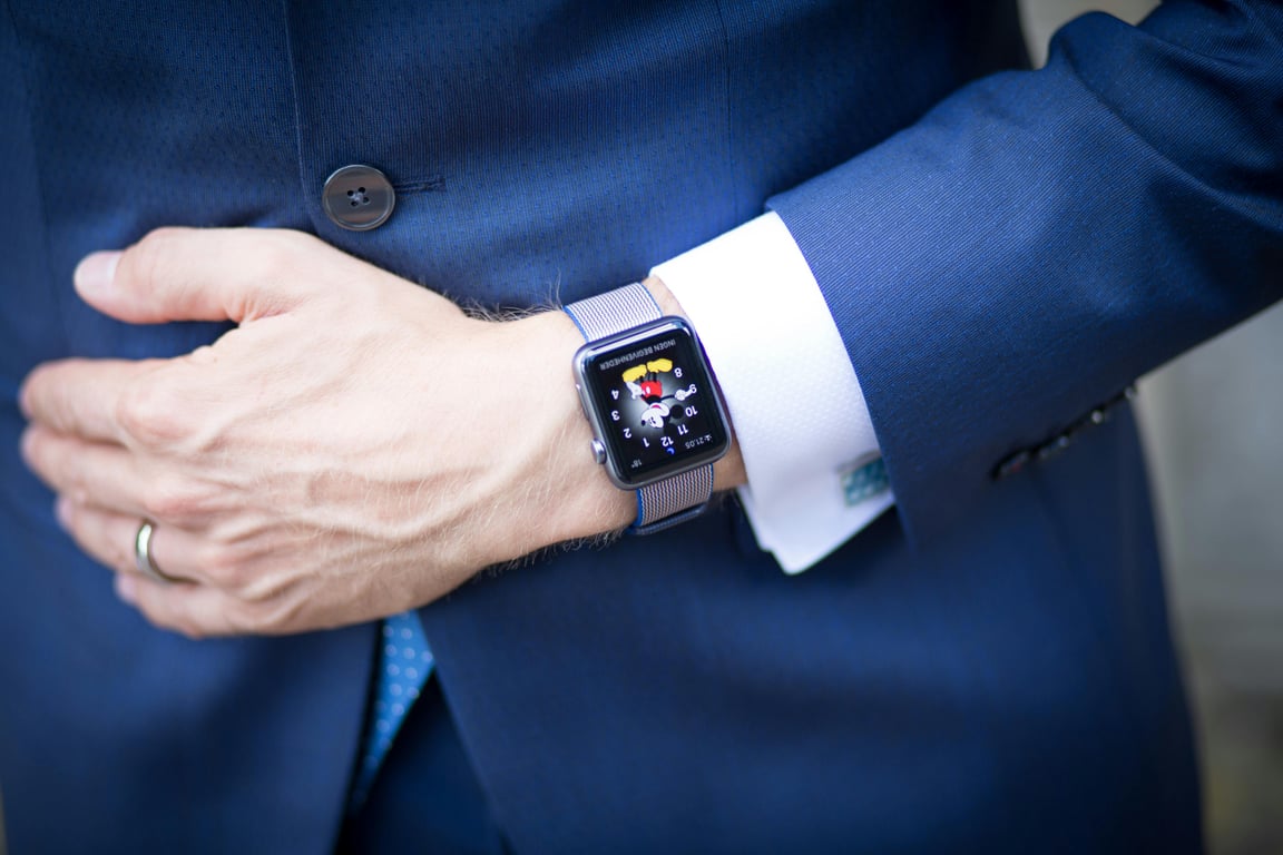 A businessman in a blue suit wearing a smartwatch, symbolizing modern technology in the corporate world.