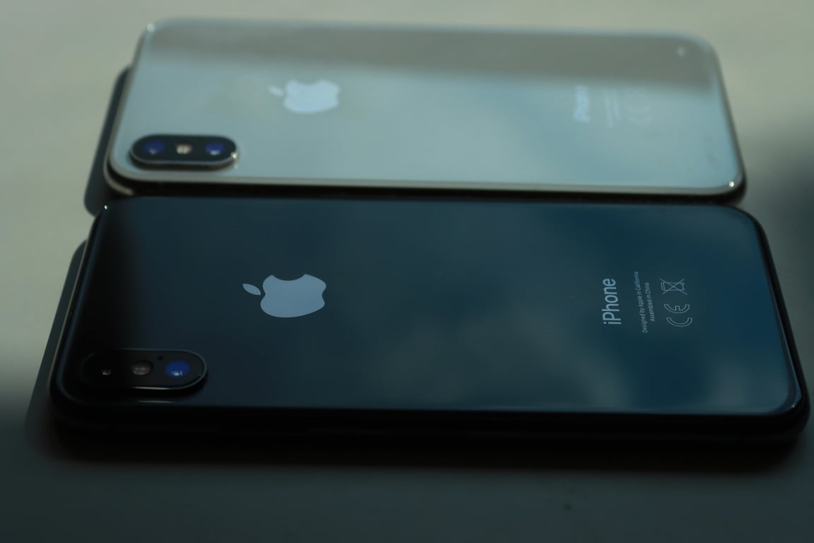 Close-up of two smartphones displayed on a table in muted lighting, showcasing sleek design.
