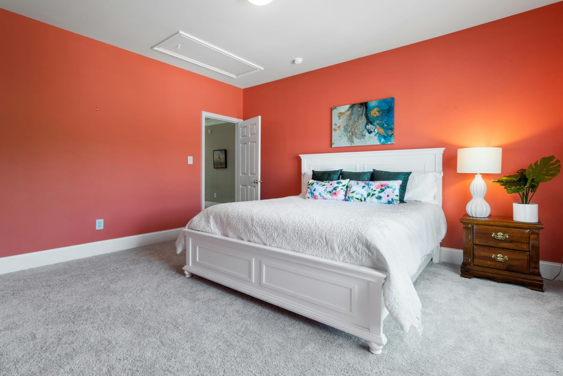Stylish bedroom featuring a coral accent wall and elegant white furniture.
