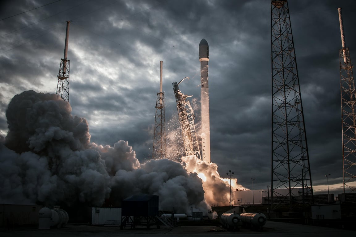 Smoke billows as a rocket launches into a dramatic evening sky, showcasing technological innovation.
