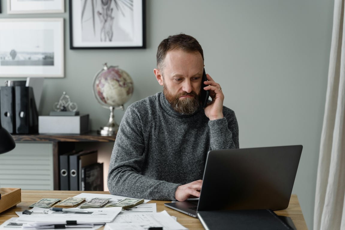 Adult businessman working in modern office with laptop and phone.