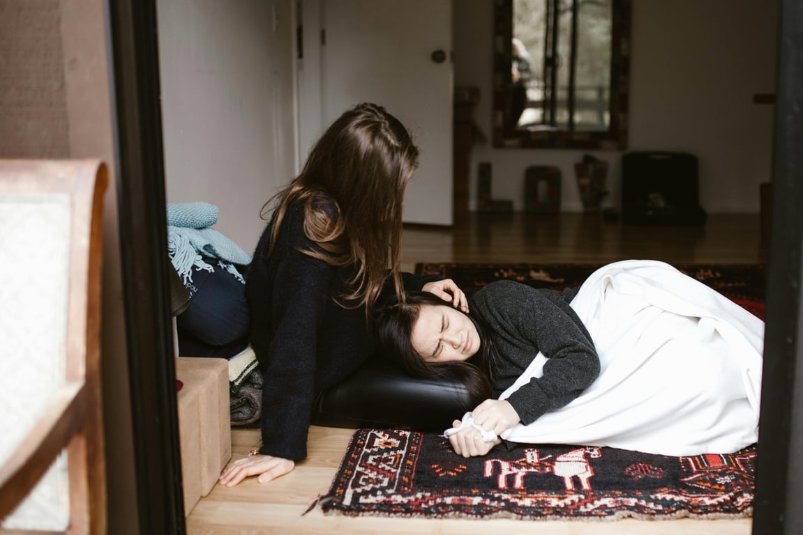 A woman comforts another during an emotional moment indoors, evoking themes of empathy and support.