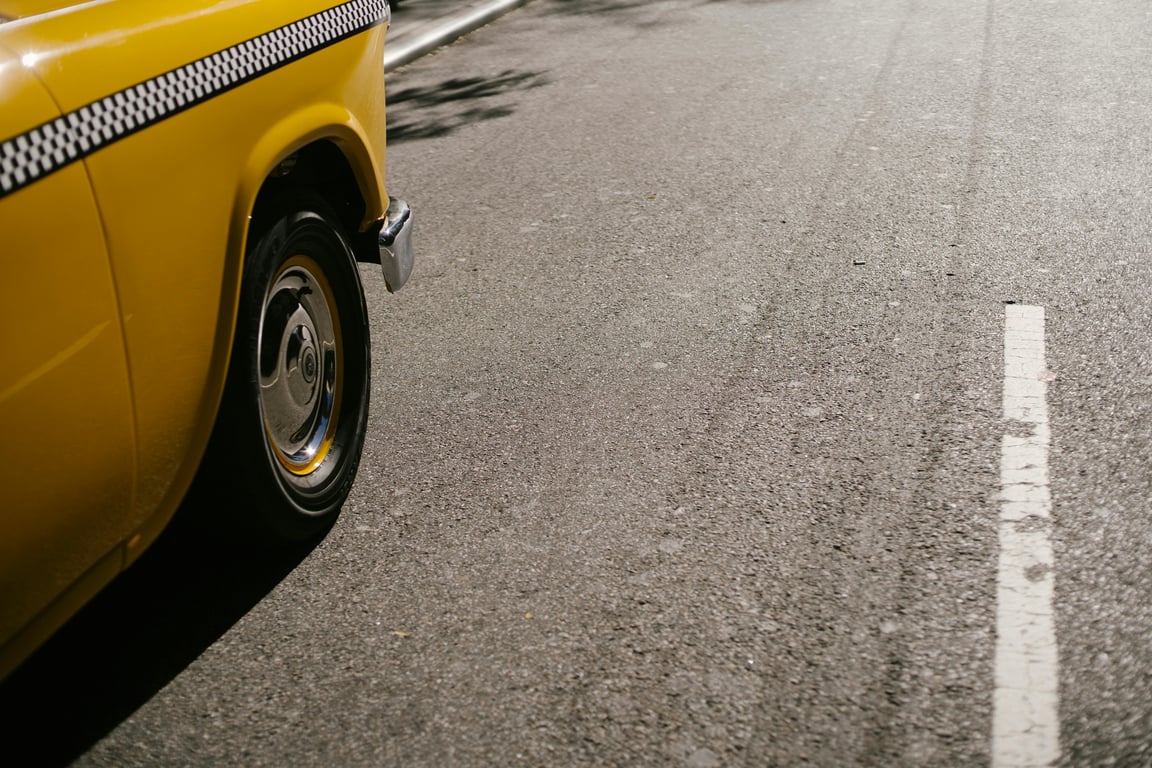 From above of shiny yellow cab driving along street on asphalt roadway in modern city in soft daylight
