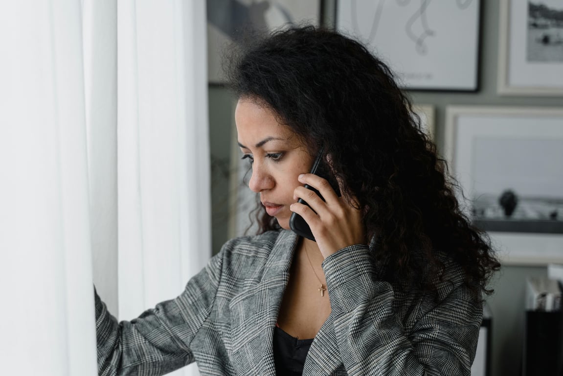 Businesswoman gazes outside while talking on the phone in an office setting.